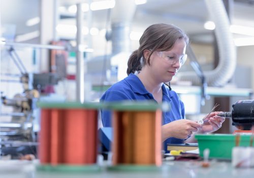 Female worker assembling electromagnetic coils in electronics factory